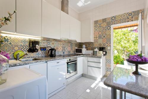 a kitchen with white cabinets and a sink and a window at Casa Portugueza Experience in Porto