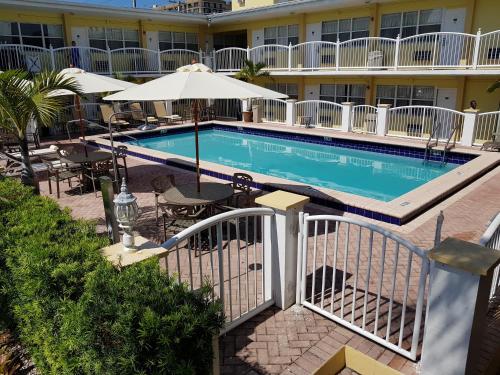 a swimming pool with tables and an umbrella next to a hotel at Beach Place Hotel in Miami Beach
