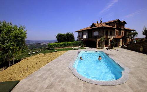 two people in a swimming pool in front of a house at Agriturismo Il Bricco in Treiso