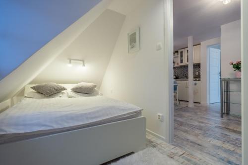 a white bedroom with a bed and a staircase at Pensjonat Magdalena in Szklarska Poręba