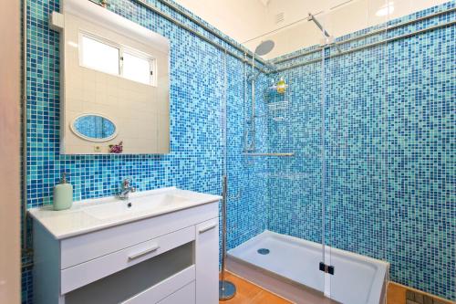 a blue tiled bathroom with a sink and a shower at Casa Portugueza Experience in Porto
