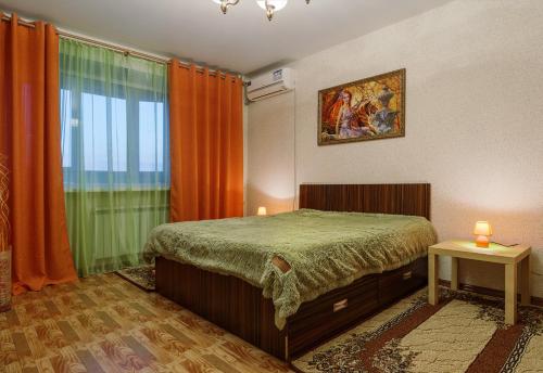 a bedroom with a bed and a window with orange curtains at Apartment On Perevertkina 24а in Voronezh