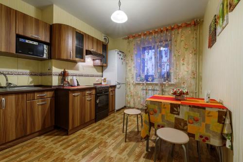 a kitchen with wooden cabinets and a table with stools at Apartment On Perevertkina 24а in Voronezh