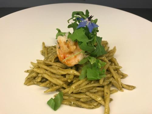 a plate of food with pasta with shrimp and greens at Hotel Stüa Granda in Soglio
