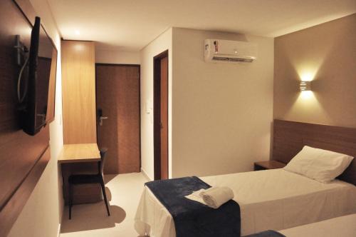ゴイアニアにあるRainha Hotelのベッドと椅子が備わる小さなホテルルームです。