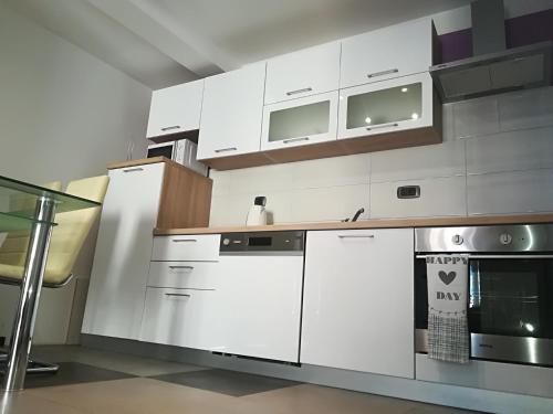 uma cozinha com armários brancos e um fogão em Apartman Brzović em Omiš