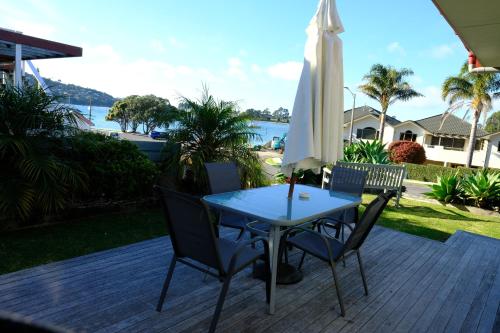 a table and chairs on a patio with an umbrella at Tairua Shores Motel in Tairua