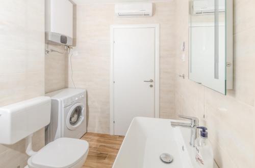 een witte badkamer met een wasmachine en een wastafel bij Down town oaza in Rijeka