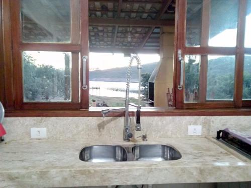 un lavandino in cucina con due finestre di rancho california a Delfinópolis