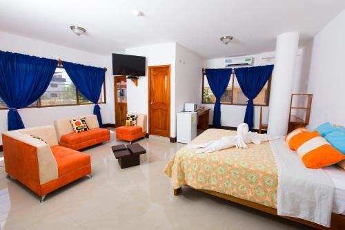 una camera con due letti, una sedia e un divano di Hostal Tongo Reef a Puerto Baquerizo Moreno
