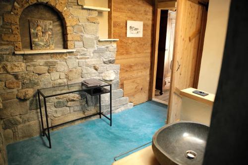 baño con pared de piedra y lavamanos en La casa di paglia B&B, en Verrayes
