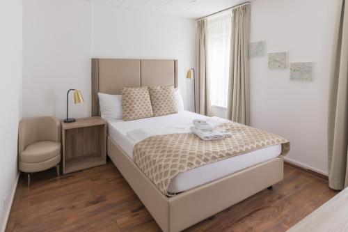 ein Schlafzimmer mit einem großen Bett und einem Stuhl in der Unterkunft Residence Mutschellen in Zürich