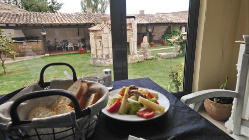a table with a plate of food and a basket of bread at Amanecer en Campos in Población de Campos