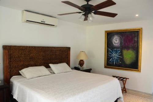 a bedroom with a white bed with a ceiling fan at Hotel Boutique Villa Casuarinas in Cali