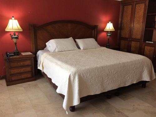 a bedroom with a large bed with two lamps at Hotel Boutique Villa Casuarinas in Cali
