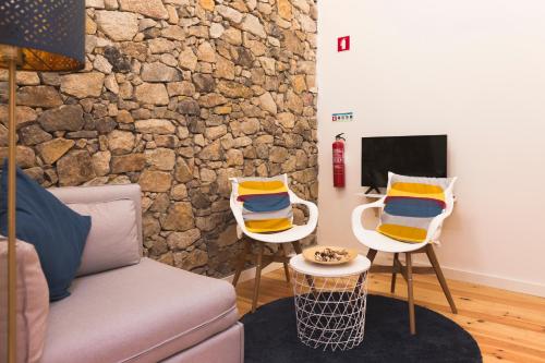 uma sala de estar com duas cadeiras e uma parede de pedra em APOSENTUS - Your home with a remarkable view em Vila Nova de Gaia