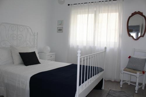 een witte slaapkamer met een bed en een raam bij Jardim à vista in Aveiro