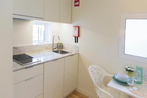 uma cozinha branca com um lavatório e uma mesa em APOSENTUS - Your home with a remarkable view em Vila Nova de Gaia