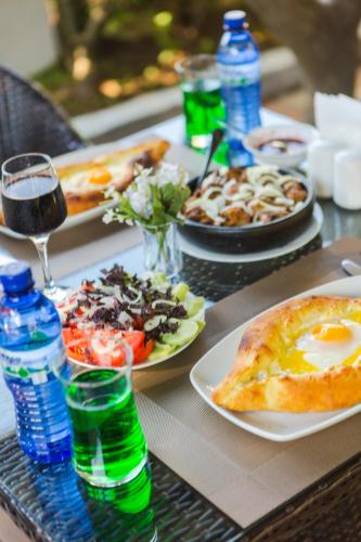 a table with plates of food and a glass of wine at Hotel Simpatia in K'obulet'i