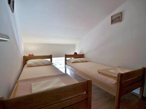 two twin beds in a room with a window at Apartmani Roza Lopar in Lopar