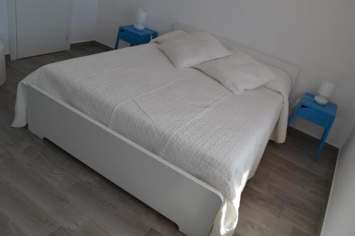 a white bed with two blue night stands next to it at Casa Sara in Acireale
