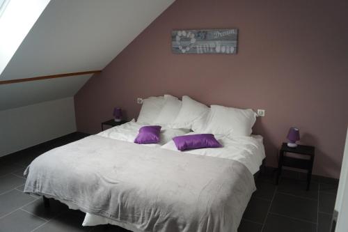 a bedroom with a white bed with purple pillows at La Schleif in Hazelbourg