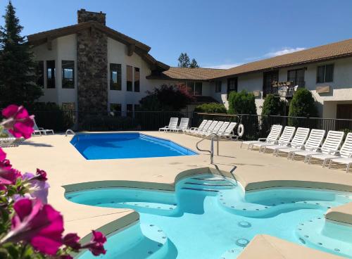 a swimming pool in front of a building with chairs at Enzian Inn in Leavenworth