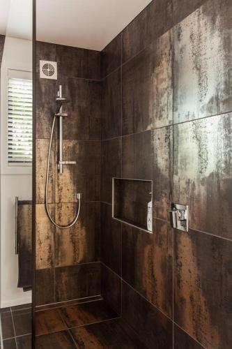 a bathroom with a shower with a wooden wall at Black Luxury Lodge in Blenheim