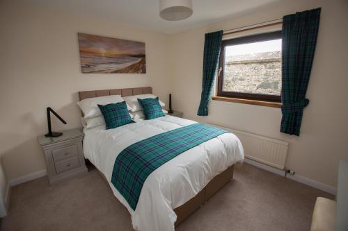 a bedroom with a bed with blue pillows and a window at Golfview in Buckie