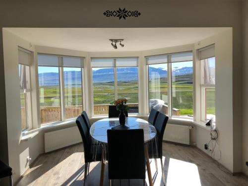 a dining room with a table and chairs and windows at Grýtubakki I in Grenivík
