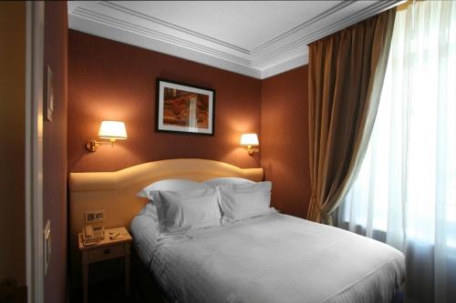 1 dormitorio con cama blanca y ventana en Hôtel Princesse Flore, en Royat