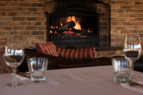 a table with wine glasses in front of a fireplace at Bowen Inn Motel in Lithgow