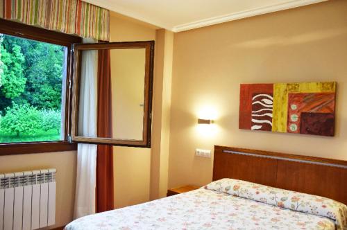 - une chambre avec un lit et une grande fenêtre dans l'établissement Apartamentos La Barzana, à Barro de Llanes