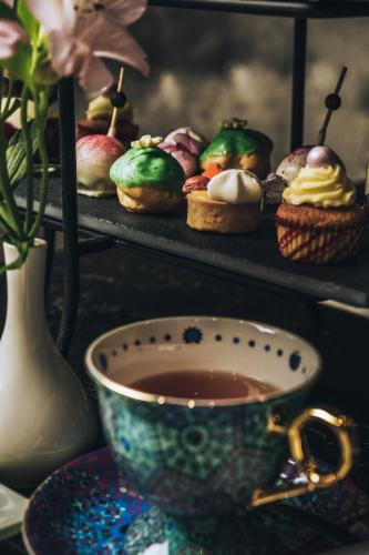 a cup of tea next to a plate of cupcakes at Fable Auckland, MGallery in Auckland