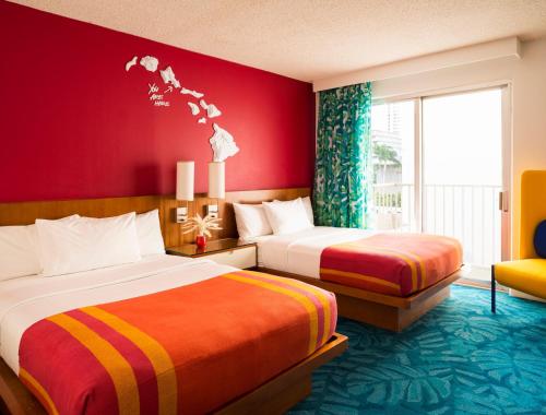 two beds in a hotel room with red walls at Shoreline Hotel Waikiki in Honolulu