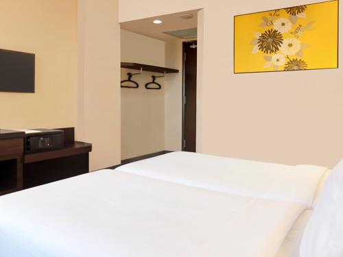 a bedroom with a white bed and a tv at Hotel Summer View in Kuala Lumpur