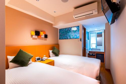 a hotel room with two beds and a television at Ueno Hotel in Tokyo