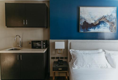 ドゥマゲテにあるPVL Suitesのベッド、シンク、キッチンが備わるホテルルームです。