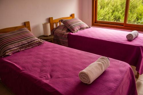 two beds with pink sheets in a room with a window at Cabañas Mirasoles in Villa General Belgrano
