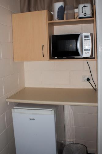 a microwave sitting on a shelf above a refrigerator at Motel Kempsey in Kempsey