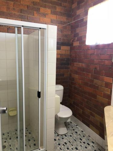 a bathroom with a toilet and a glass shower at Glen Innes Lodge Motel in Glen Innes