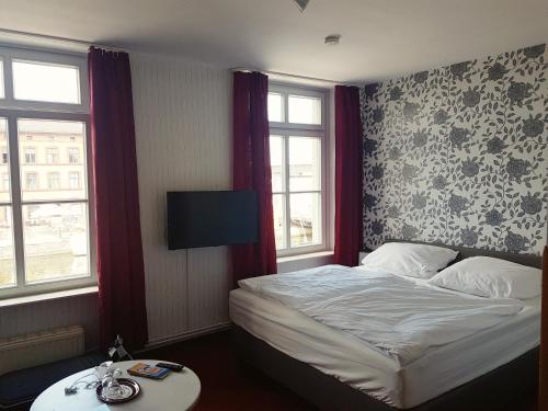 a hotel room with a bed and two windows at Pension Klabautermann in Stralsund