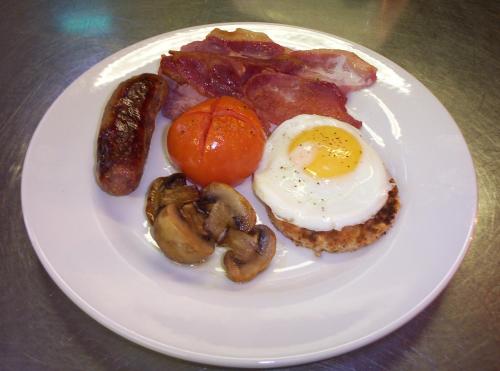 a plate of food with eggs bacon mushrooms and tomatoes at Farnham House Hotel in Farnham