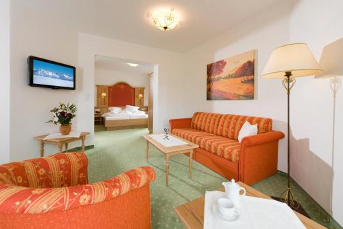 a living room with a couch and a bed at Landhotel Föhrenhof Ellmau in Ellmau