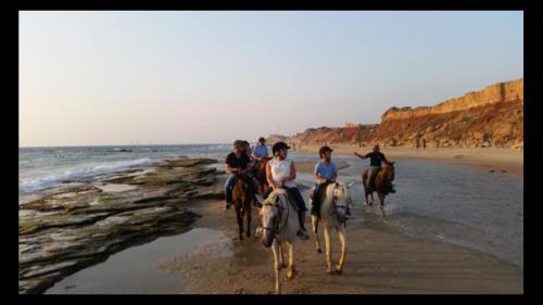 a group of people riding horses on the beach at Caravans through the nature in Mikhmoret