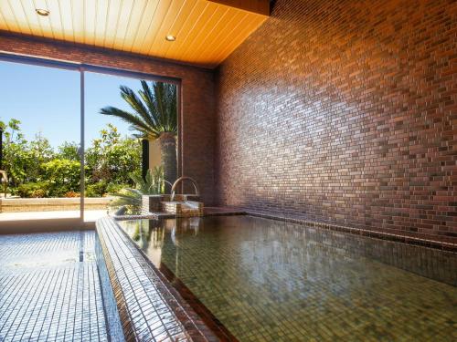- une piscine dans une maison dotée d'un mur en briques dans l'établissement Minato Koyado Awajishima, à Minamiawaji