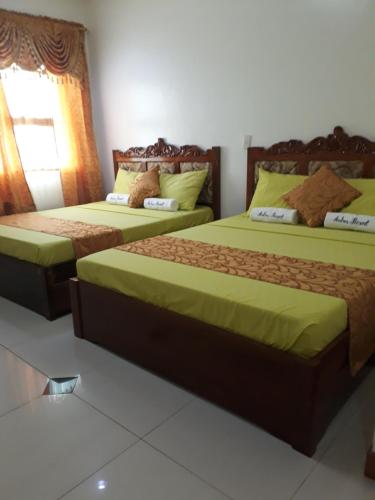 a bedroom with two beds with green sheets and a window at Andres Resort in Nabas