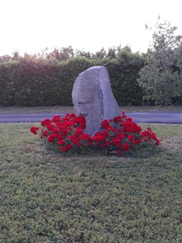 a statue of a head with red flowers in the grass at L'Orto sul Poggio in Sutri