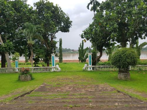 a park with a white fence and trees at Royal Mekong Riverside Hotel in Nong Khai