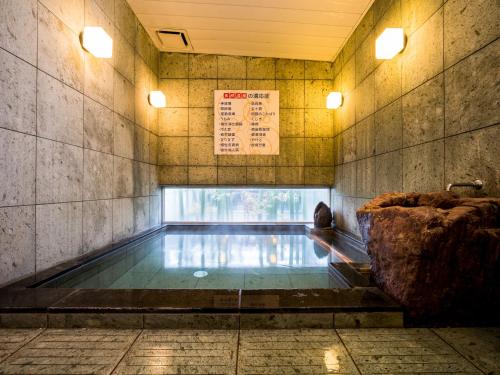 a swimming pool in a building with a sign on the wall at Super Hotel Niihama in Niihama